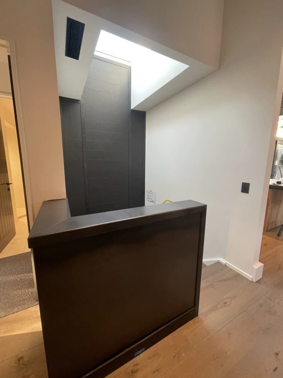 Cabinet clad in blackened steel with a folded edge, beside a timber-lined ceiling