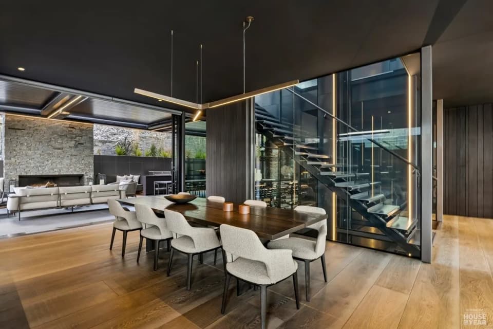 Glazed feature staircase with dark steel structure beside a dining room, Queenstown