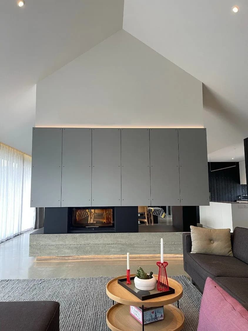 Front view of a folded steel panel fireplace with a low concrete hearth and a linear firebox