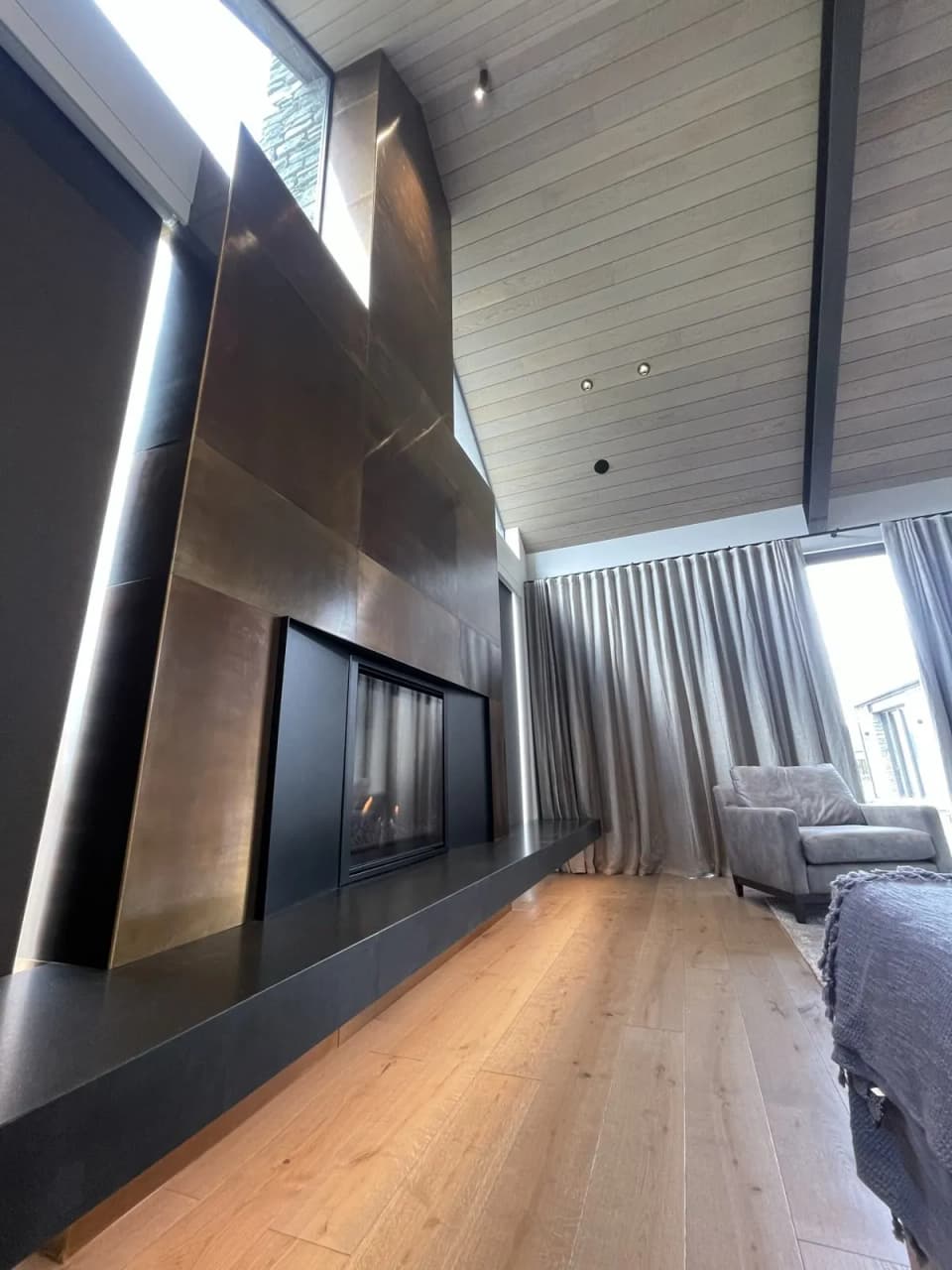 Side view of a patinated steel chimney cladding, showing the folded panel joints and firebox opening