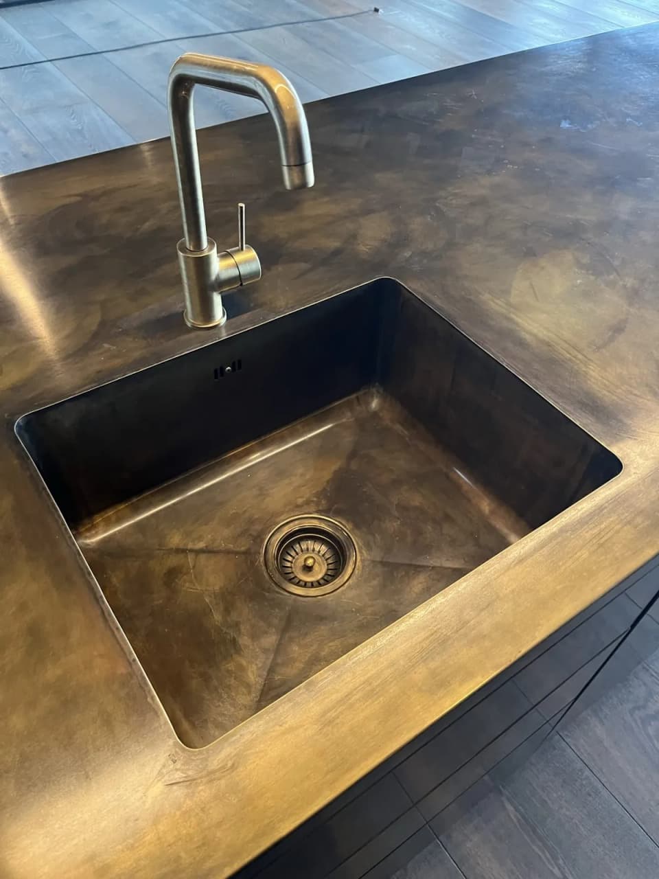 Integrated sink and benchtop in patinated brass with a brass tap