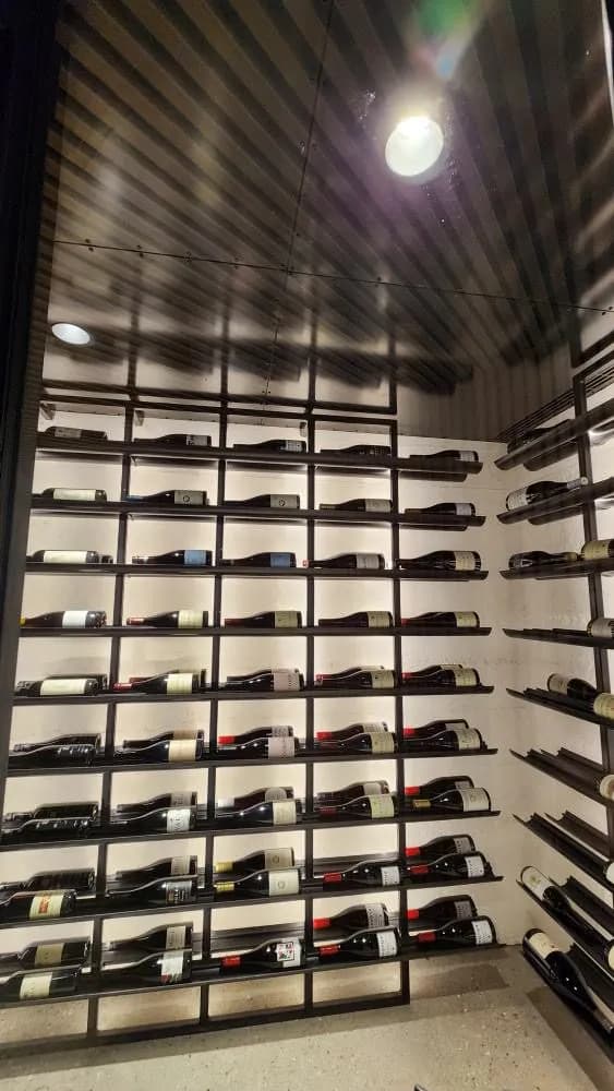 Wine cellar with full-height black steel racking holding bottles on pins